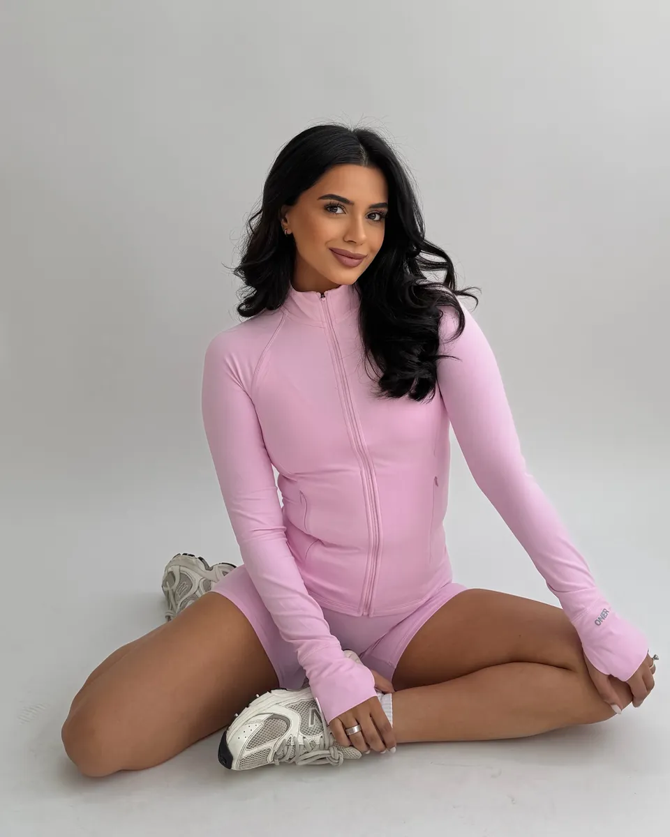 Cheri sitting cross-legged in a pink training set, smiling